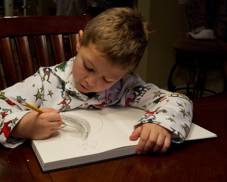 Grant Kish drawing his first picture in his drawing book.