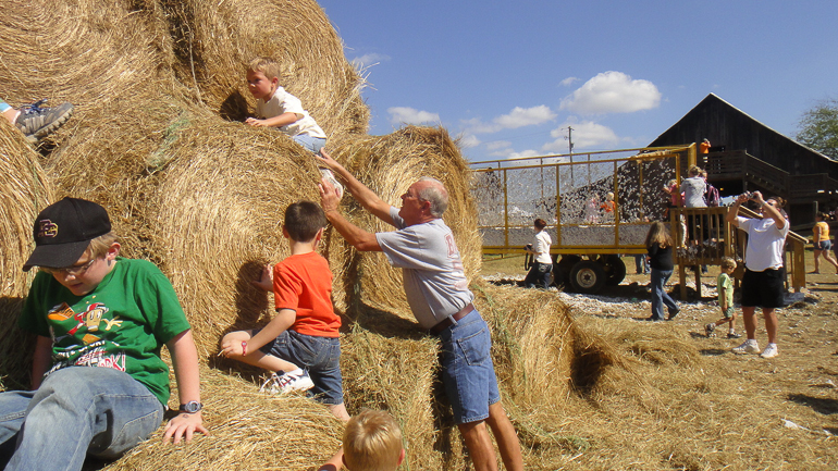 Dan Gibson helps Grant Kish up the hay bales, Old Baker Farm, Harpersville, AL.